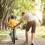 father teaching child how to ride a bike